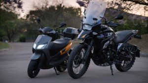 A 125cc sports scooter and a small adventure motorcycle parked side by side, the two kinds of bike this Suzuki comparison weighs up