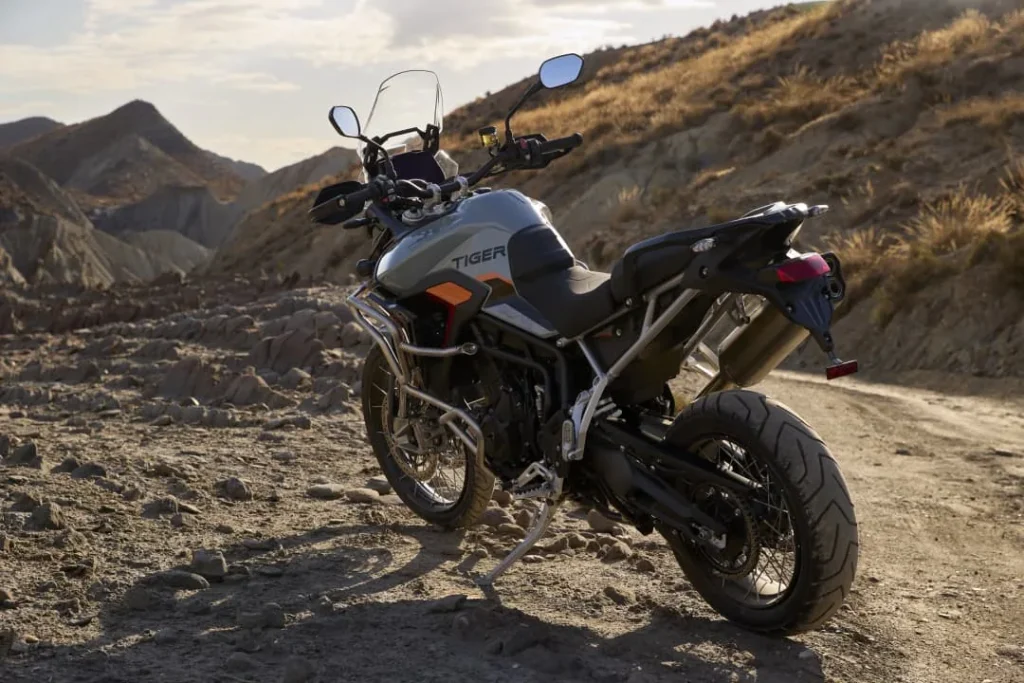 Triumph Tiger 900 Desert Edition in Urban Grey with Baja Orange accents parked on a gravel road
