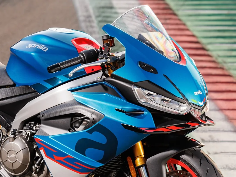 Close-up of the nose, screen, clip-on bars and front winglet of a blue Aprilia RS 660 Factory at a race track