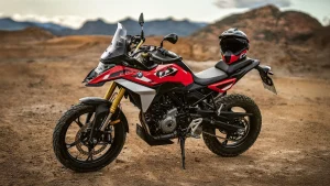 BMW F 450 GS Sport in Racing Red parked on a dirt plateau with hills behind and a helmet on the seat, seen from the left side