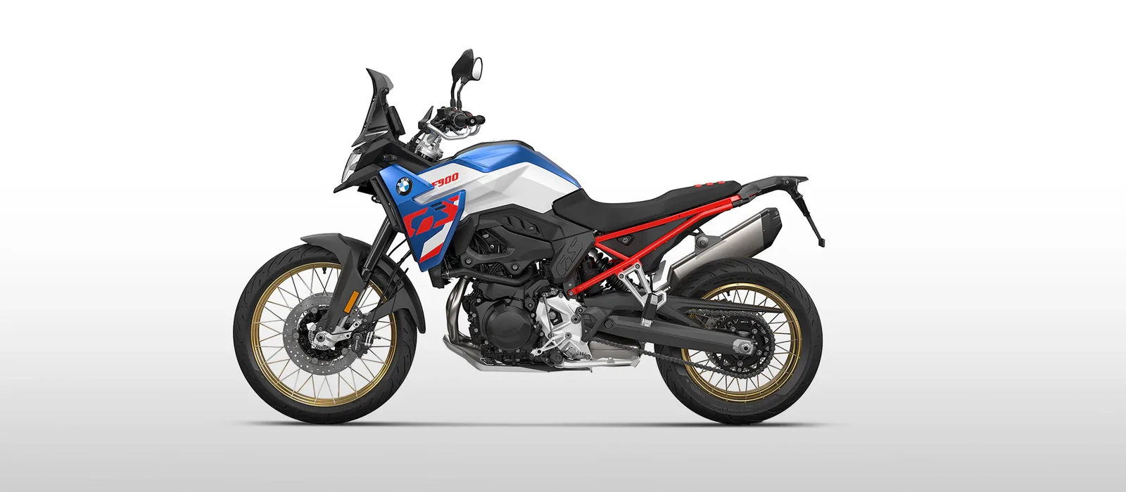 Studio side view of the BMW F 900 GS in GS Trophy style, white and Racing Blue with a red frame and gold spoked wheels