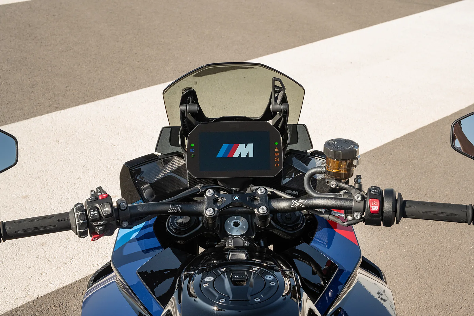 View over the handlebars of the BMW M 1000 XR showing the 6.5 inch TFT with the M start-up logo, bar-end mirrors and tinted screen
