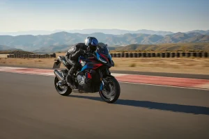 Rider in black leathers on a BMW M 1000 XR in black with M colours cornering on a race track with mountains behind