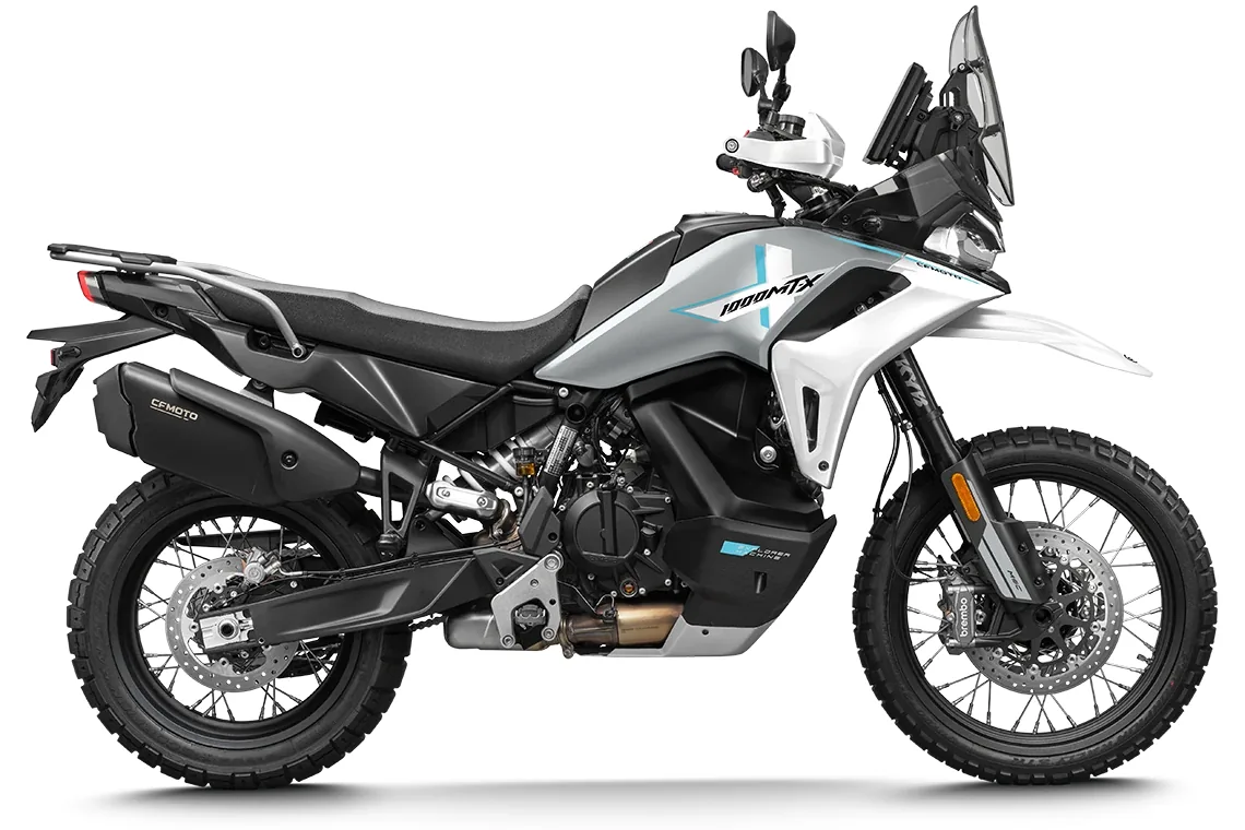 Studio side view of the CFMoto 1000MT-X in Aerolite Grey with blue graphics, seen from the right, showing the exhaust, rear rack and upright TFT screen