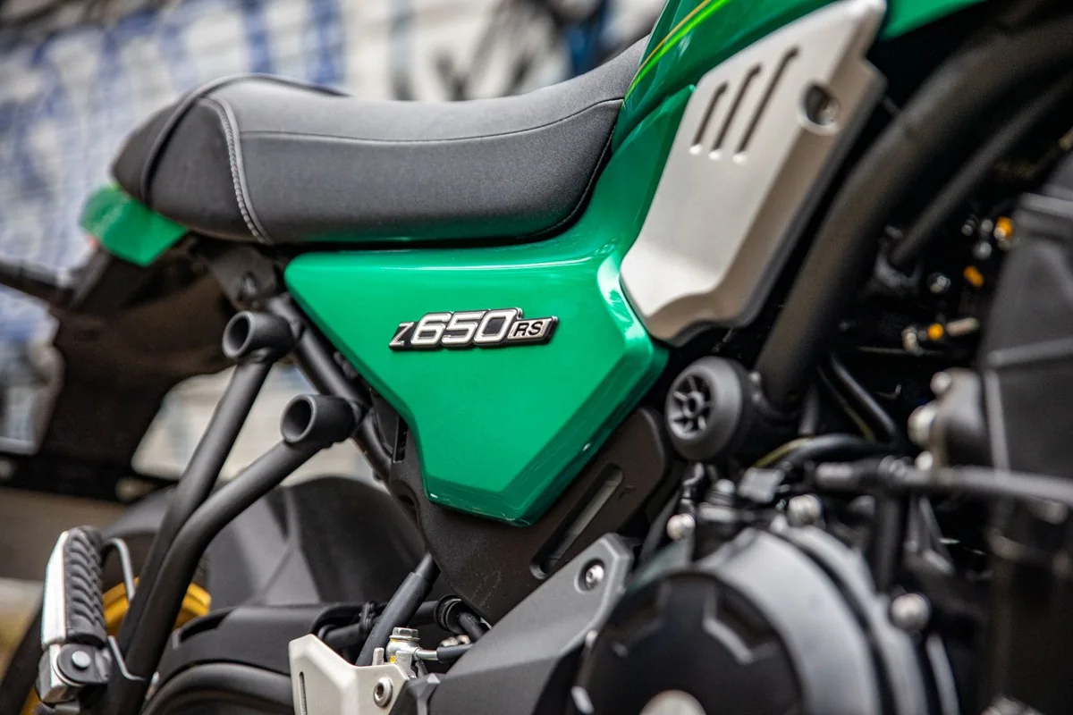 Close-up of the green Kawasaki Z650RS side panel with its Z650RS badge, the seat and the silver frame cover