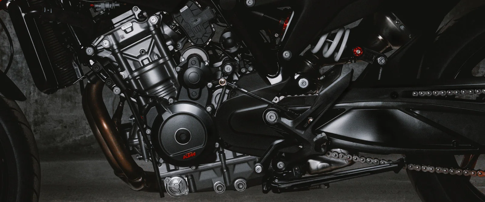 Close-up of the black LC8c parallel-twin engine of the KTM 790 Duke with the exhaust header, clutch cover, rear shock spring and chain