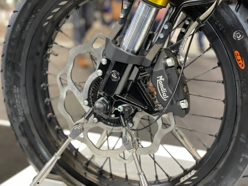 Close view of the Mondial HPS 125 Ubbiali front wheel showing the wave disc, Mondial-branded radial four-piston caliper, ABS sensor ring and CST tyre