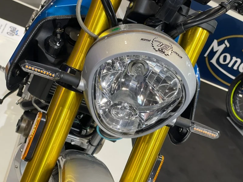 Close view of the Mondial HPS 125 Ubbiali round headlight with the 1951 to 2021 seventieth anniversary laurel badge, gold fork legs and LED indicators