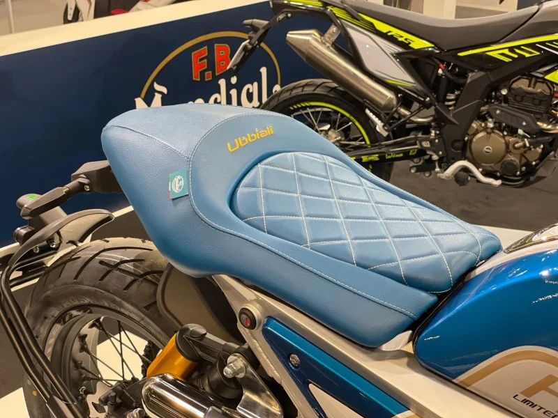 Close view of the Mondial HPS 125 Ubbiali light blue quilted seat with diamond stitching and the Ubbiali name embroidered in gold