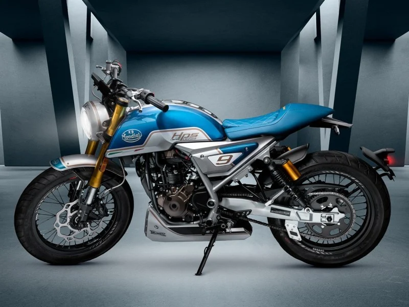 Left side profile of the Mondial HPS 125 Ubbiali Limited in a studio, showing the light blue tank, silver side plate with number 9, gold upside-down fork, twin shotgun exhausts, quilted blue seat and spoked wheels