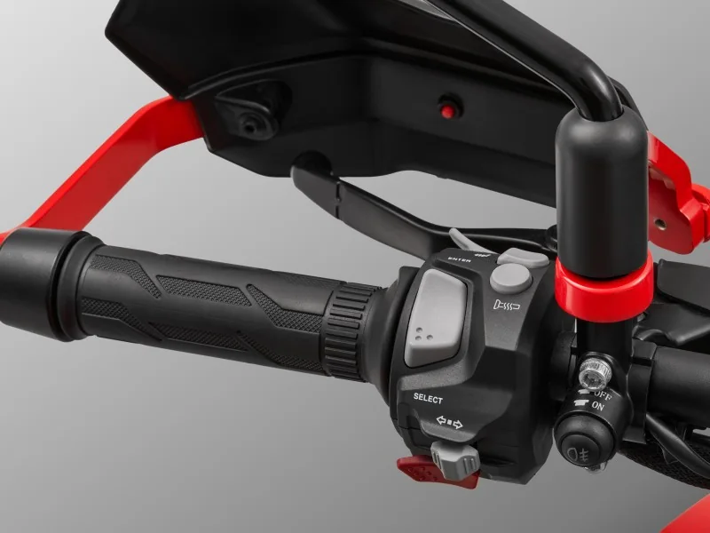 Left handlebar of the QJMotor SRT 600 showing the heated grip, switchgear with select and enter buttons, red hand guard frame and auxiliary light switch