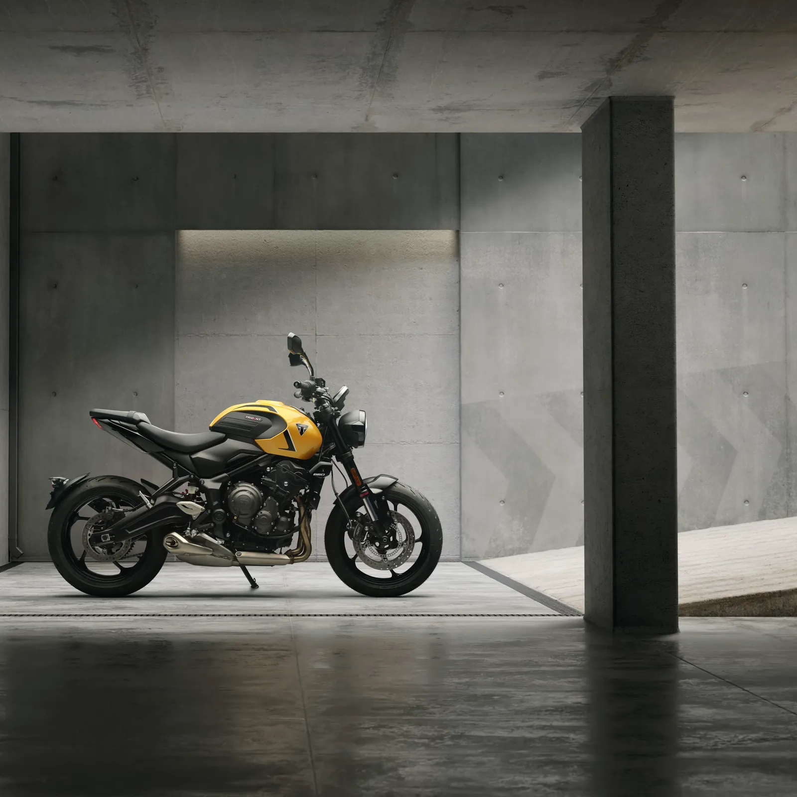 Side profile of the 2026 Triumph Trident 660 in Cosmic Yellow in a concrete building, showing the broader tank, split seat and low single-sided exhaust