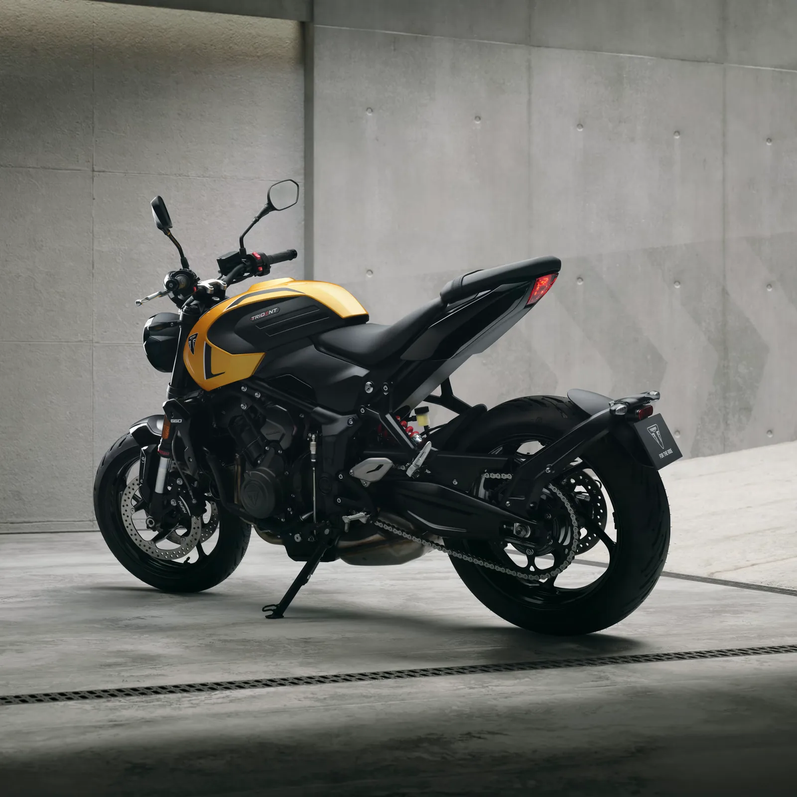 Rear three-quarter view of the yellow 2026 Triumph Trident 660 showing the 180-section rear tyre, steel swingarm and short tail