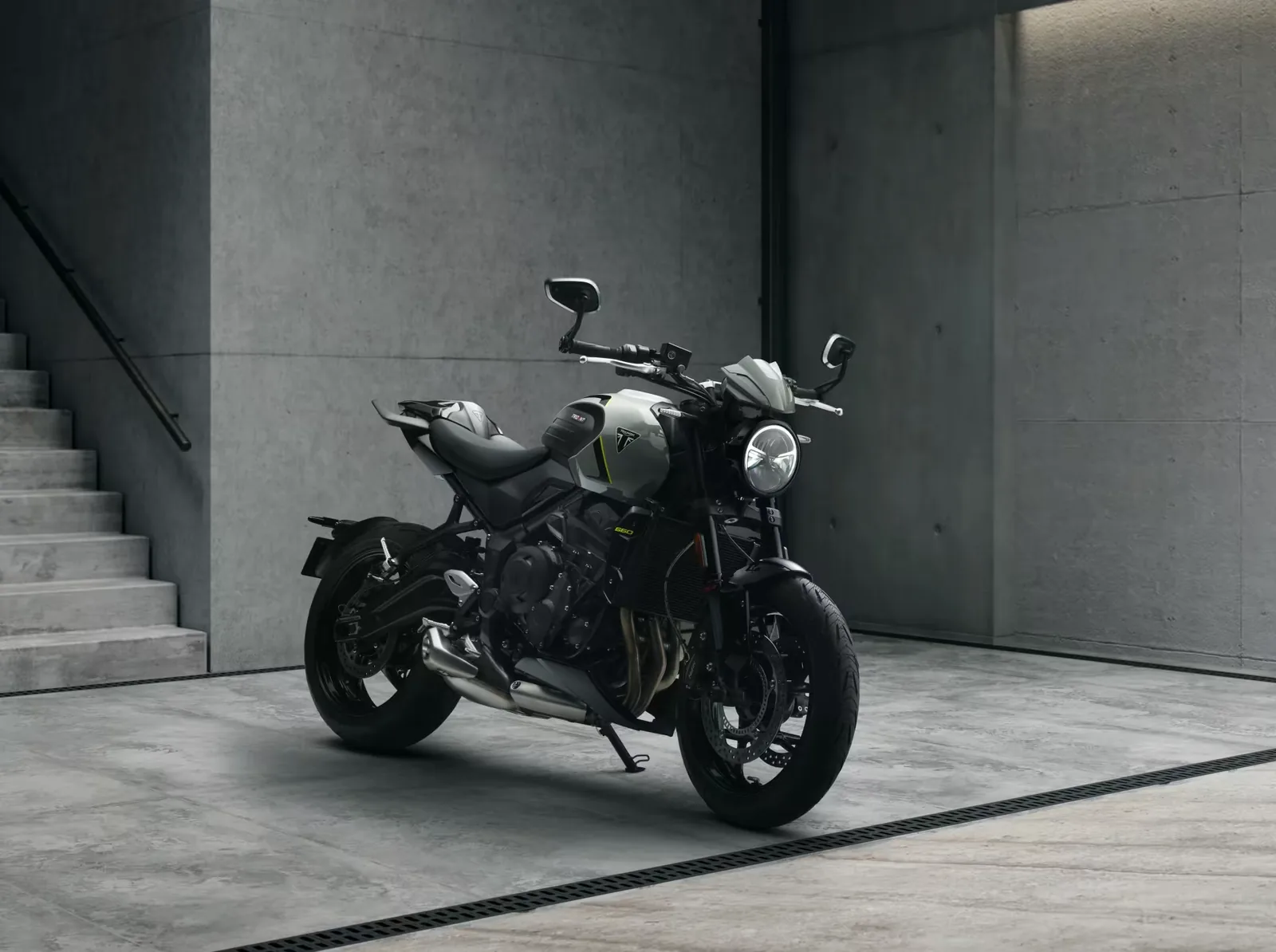 2026 Triumph Trident 660 in Snowdonia White fitted with accessory flyscreen, bar-end mirrors and bellypan, parked beside concrete stairs