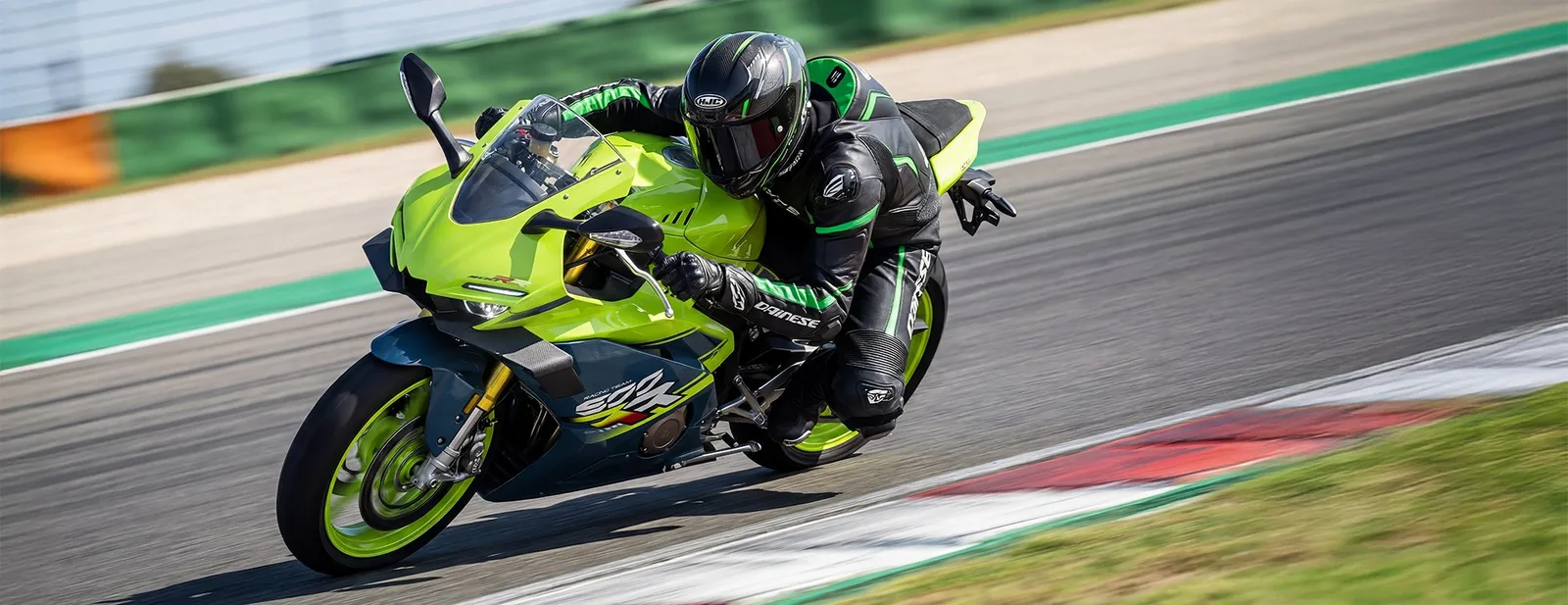 Rider in black and green leathers with knee down on a lime green ZXMOTO 500RR on a race track