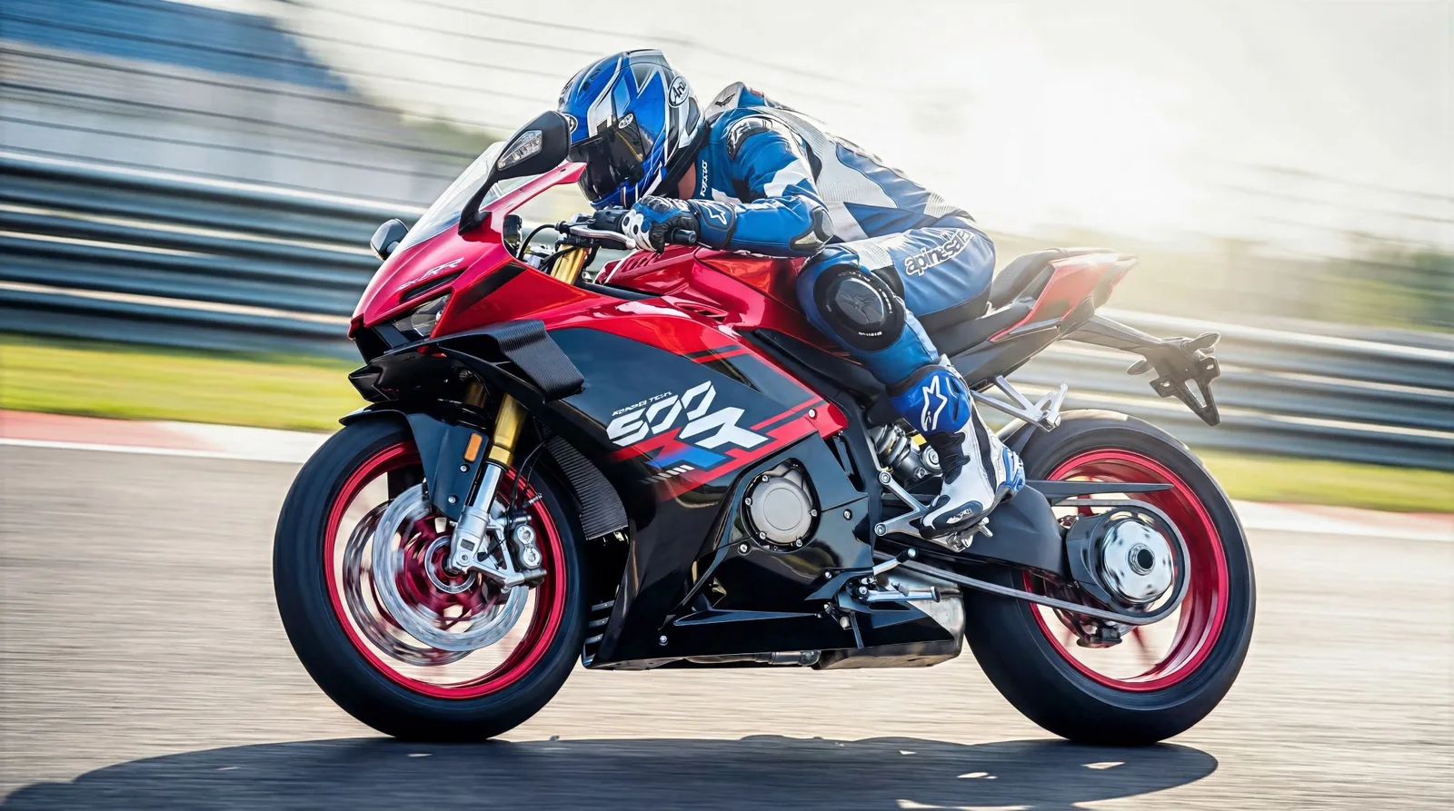 Rider in blue leathers cornering a red and black ZXMOTO 500RR on a race track with the front wheel blurred