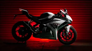 ZXMOTO 500RR sportsbike in white on a paddock stand in a dark studio lit red from behind, showing the single-sided swingarm and winglets